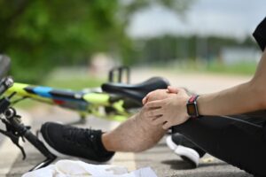 Male cyclist having an accident, falling down from bicycle and injured his knee. Bicycle accident